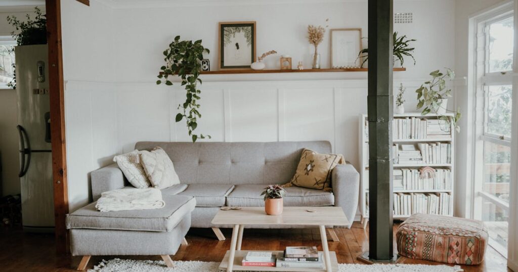 Skandinavisk indrettet stue med grå sofa, bogreol og planter — hjemlig stemning der illustrerer overvejelser ved boligkøb.
